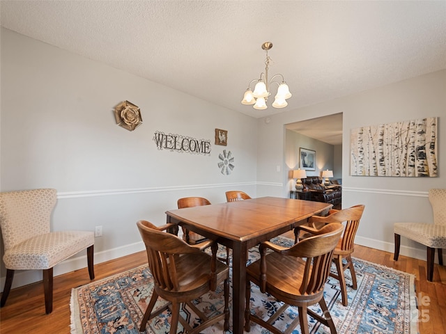 dining area with a chandelier, a textured ceiling, and hardwood / wood-style flooring