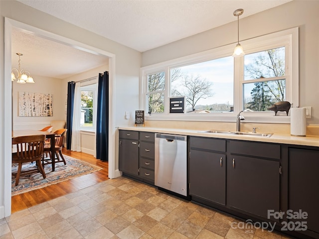 kitchen featuring sink, stainless steel dishwasher, a notable chandelier, a textured ceiling, and decorative light fixtures