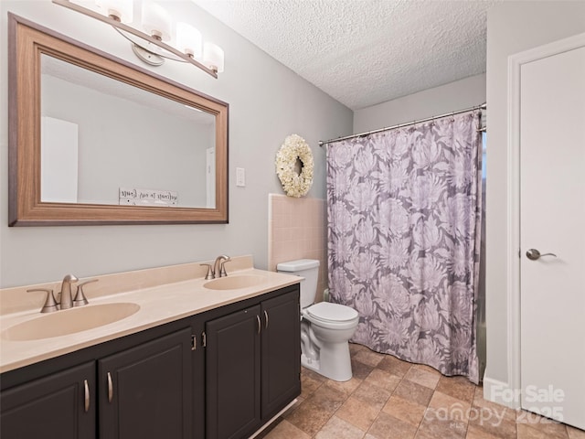 full bathroom with vanity, shower / bath combination with curtain, toilet, and a textured ceiling