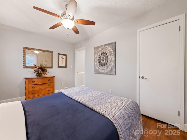 bedroom with ceiling fan, dark hardwood / wood-style floors, and a textured ceiling