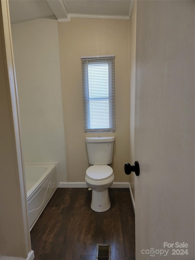 bathroom featuring hardwood / wood-style floors, toilet, a bath, and a textured ceiling