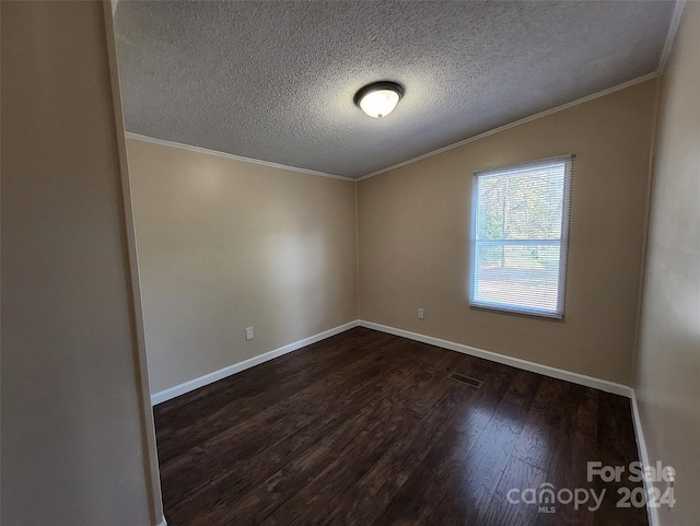 spare room with a textured ceiling, crown molding, and dark wood-type flooring