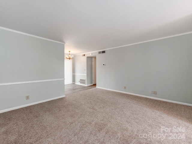 carpeted empty room featuring crown molding and an inviting chandelier