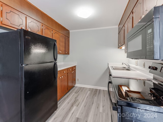 kitchen with ornamental molding, light hardwood / wood-style flooring, black appliances, and sink