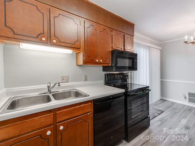 kitchen with light wood-type flooring, crown molding, sink, black appliances, and an inviting chandelier