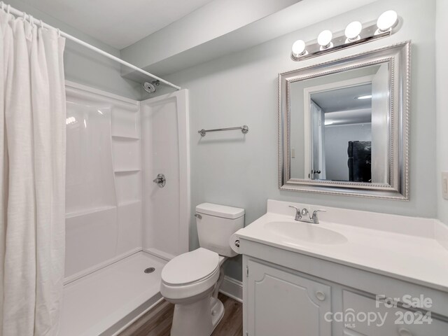 bathroom with a shower with curtain, vanity, hardwood / wood-style flooring, and toilet