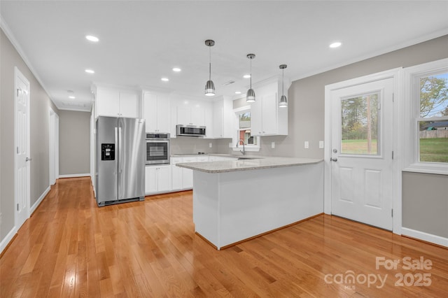 kitchen with appliances with stainless steel finishes, white cabinetry, hanging light fixtures, light hardwood / wood-style floors, and kitchen peninsula