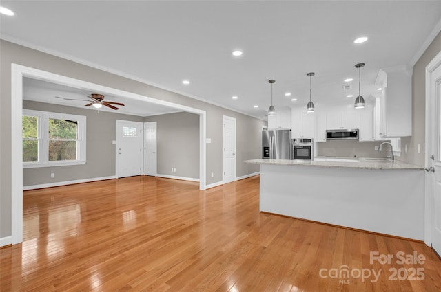 kitchen featuring appliances with stainless steel finishes, white cabinetry, hanging light fixtures, ornamental molding, and kitchen peninsula