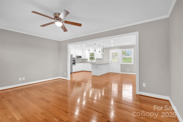 unfurnished living room featuring ornamental molding, ceiling fan, and light hardwood / wood-style flooring