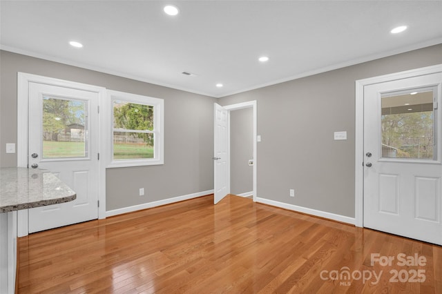 foyer entrance with crown molding and light wood-type flooring