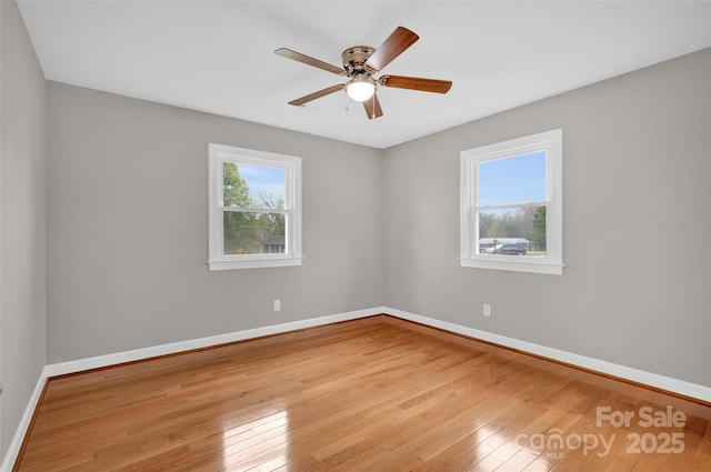 spare room with ceiling fan, a wealth of natural light, and light wood-type flooring