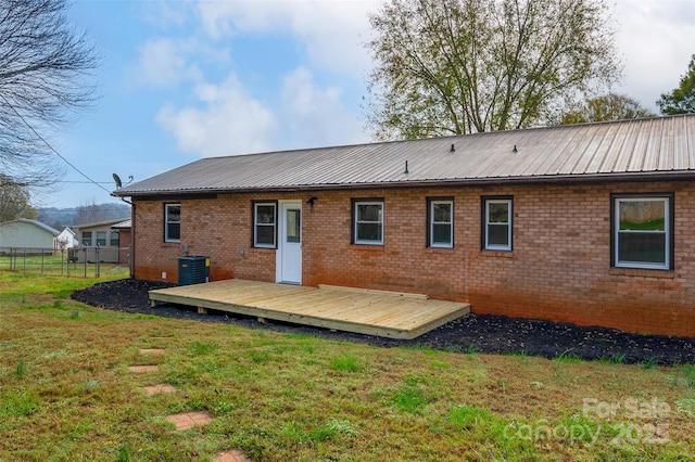 rear view of property featuring central AC, a deck, and a lawn