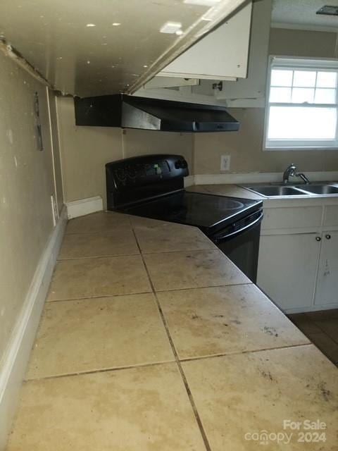 kitchen with black / electric stove, sink, white cabinets, and light tile patterned flooring