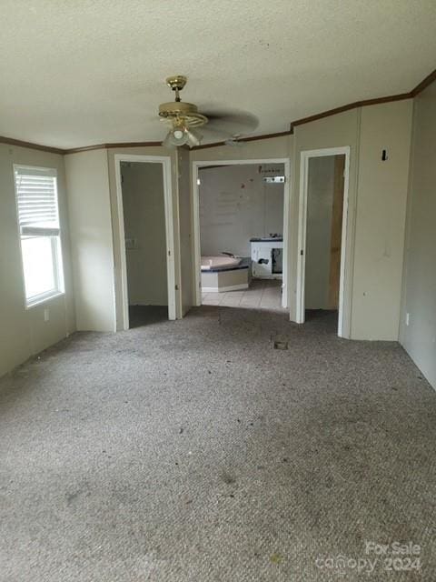 unfurnished bedroom with ceiling fan, light carpet, and a textured ceiling