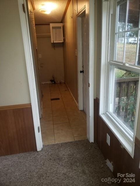 hallway featuring wood walls and light tile patterned flooring