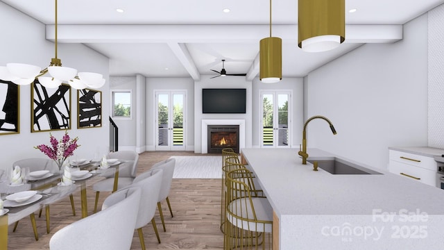 kitchen with a sink, a lit fireplace, beamed ceiling, and wood finished floors