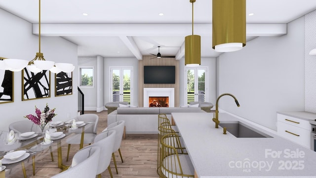 interior space with recessed lighting, baseboards, a lit fireplace, beam ceiling, and light wood finished floors