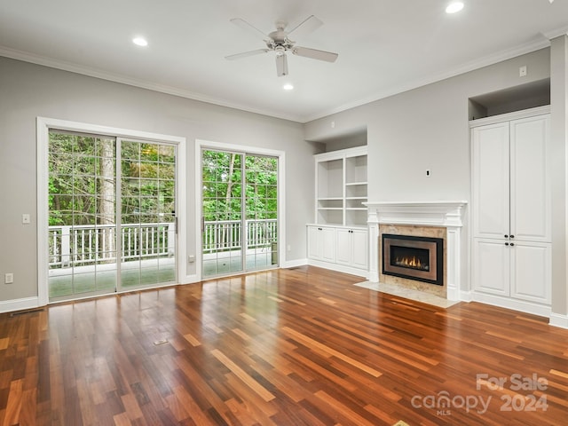 unfurnished living room with a high end fireplace, crown molding, ceiling fan, and dark wood-type flooring