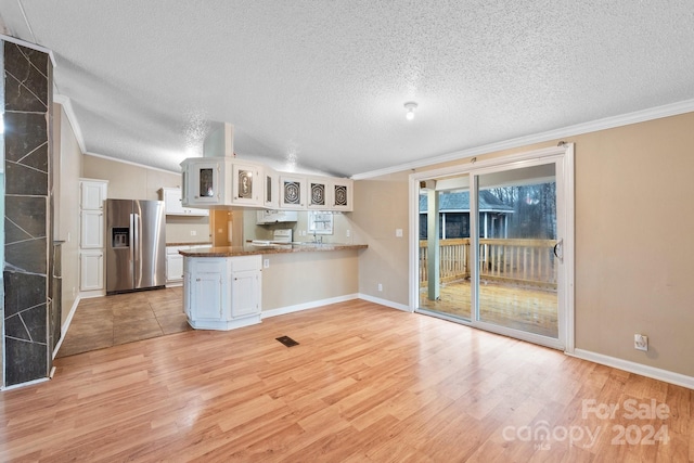 kitchen featuring kitchen peninsula, stainless steel fridge, white cabinets, and lofted ceiling