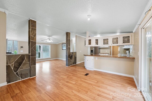 kitchen featuring crown molding, kitchen peninsula, stainless steel refrigerator with ice dispenser, light hardwood / wood-style floors, and white cabinetry