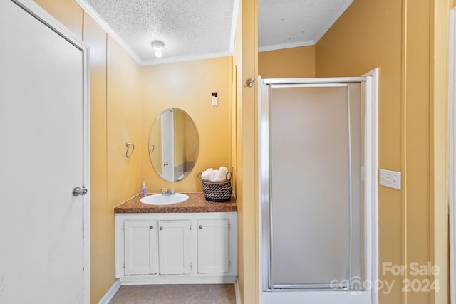 bathroom featuring a textured ceiling, vanity, a shower with door, and crown molding