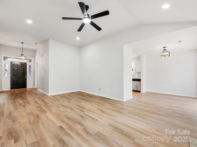 unfurnished living room with ceiling fan with notable chandelier, vaulted ceiling, and light wood-type flooring