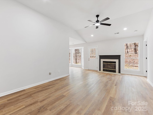 unfurnished living room featuring a high end fireplace, light hardwood / wood-style flooring, and a wealth of natural light