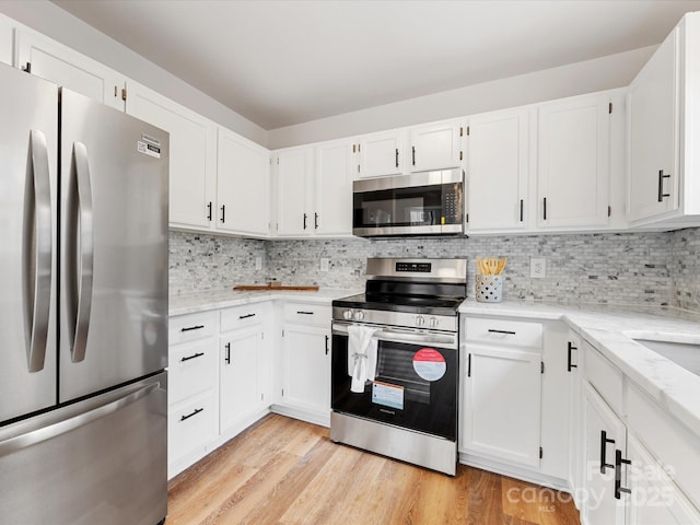 kitchen featuring appliances with stainless steel finishes, white cabinets, and light wood-type flooring