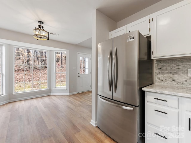 kitchen featuring light hardwood / wood-style flooring, stainless steel refrigerator, tasteful backsplash, light stone countertops, and white cabinets