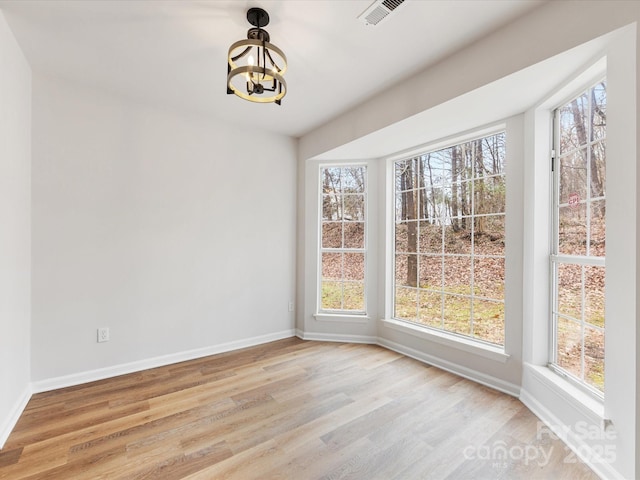 unfurnished dining area with plenty of natural light, light hardwood / wood-style floors, and a chandelier