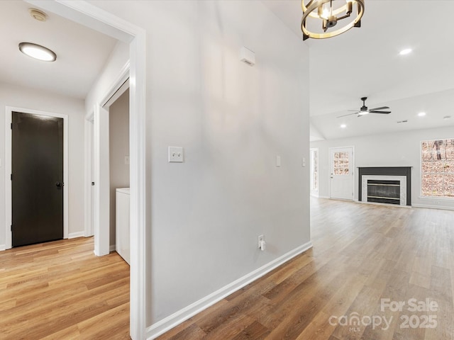 hallway with an inviting chandelier and light wood-type flooring