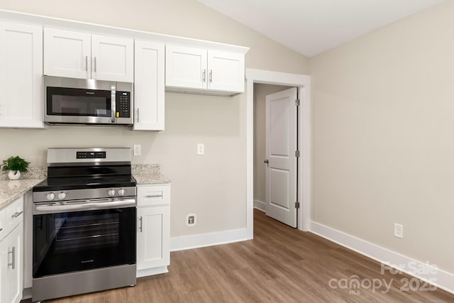 kitchen featuring white cabinets, appliances with stainless steel finishes, and light stone counters