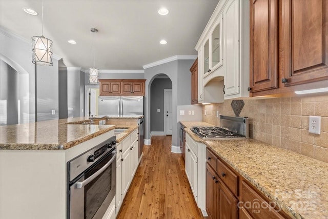 kitchen featuring pendant lighting, an island with sink, light hardwood / wood-style floors, white cabinetry, and stainless steel appliances