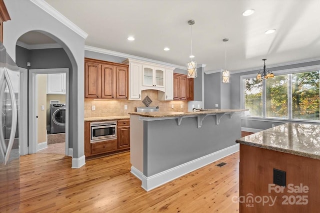 kitchen featuring light stone countertops, stainless steel microwave, washer / clothes dryer, a chandelier, and ornamental molding