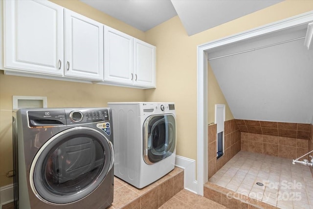 laundry room with washer and clothes dryer, light tile patterned floors, and cabinets