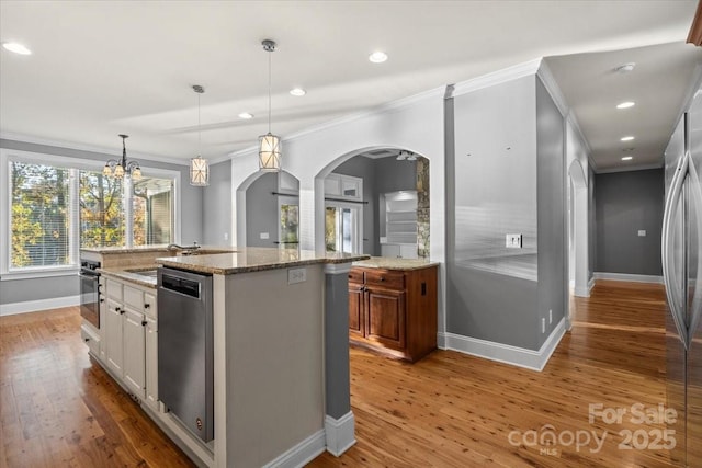 kitchen featuring stainless steel appliances, a kitchen island with sink, sink, white cabinetry, and hanging light fixtures