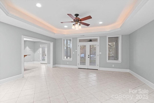 unfurnished room with ceiling fan, french doors, crown molding, a tray ceiling, and light tile patterned floors