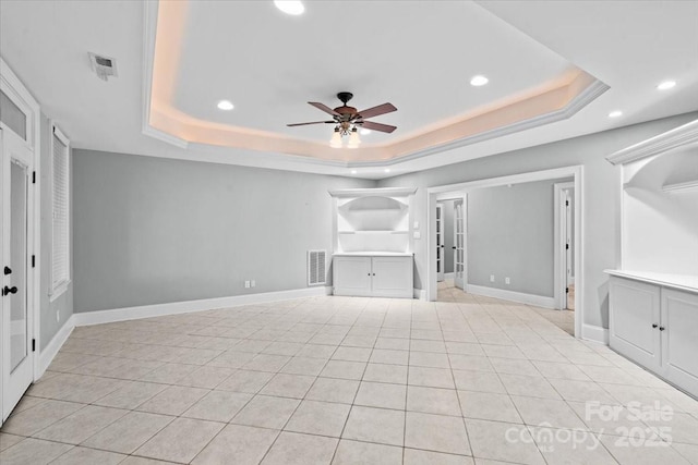 unfurnished living room featuring a raised ceiling, ceiling fan, and light tile patterned flooring