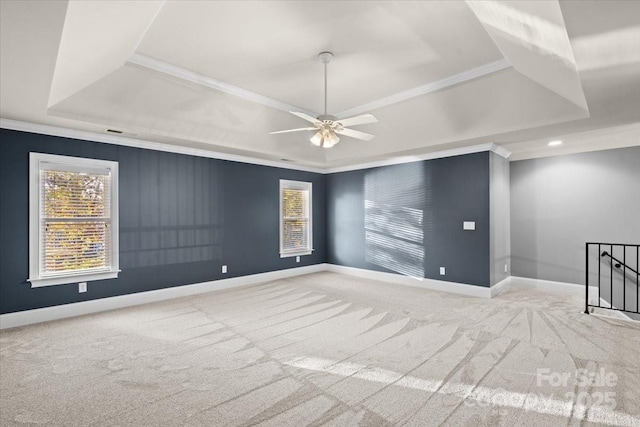 carpeted spare room featuring a tray ceiling, ceiling fan, and crown molding