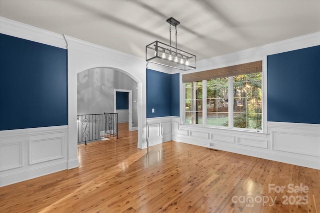 unfurnished dining area with hardwood / wood-style floors and crown molding