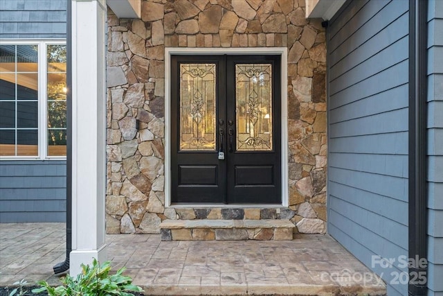 doorway to property with stone siding and french doors