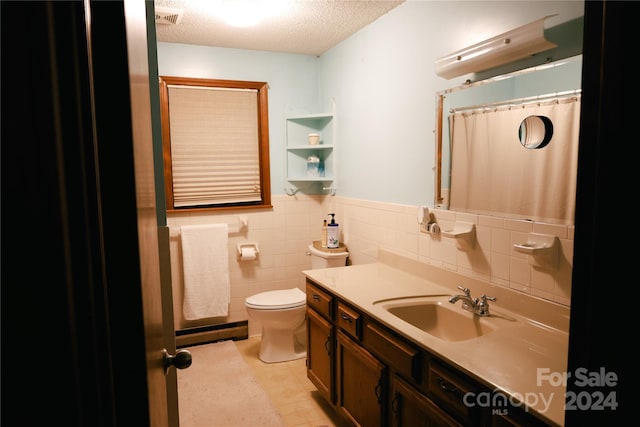 bathroom with tile patterned flooring, a textured ceiling, toilet, vanity, and tile walls