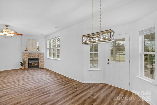 interior space with a stone fireplace, hardwood / wood-style floors, and ceiling fan