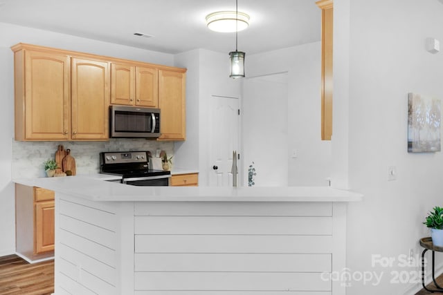 kitchen featuring appliances with stainless steel finishes, light wood-type flooring, light brown cabinets, and backsplash