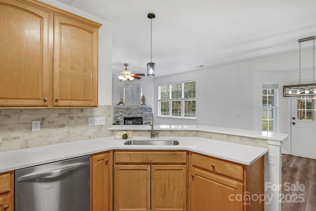 kitchen featuring decorative light fixtures, sink, decorative backsplash, stainless steel dishwasher, and kitchen peninsula