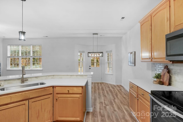 kitchen with pendant lighting, light brown cabinetry, sink, decorative backsplash, and light wood-type flooring