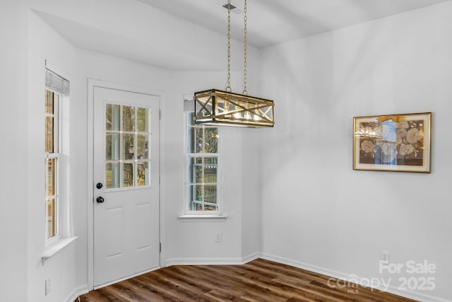 unfurnished dining area featuring dark hardwood / wood-style floors and a chandelier