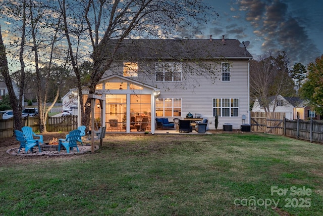 back house at dusk featuring a patio, a yard, and a fire pit