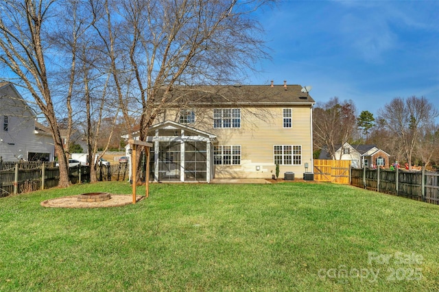 back of property with a yard, a fire pit, and a sunroom