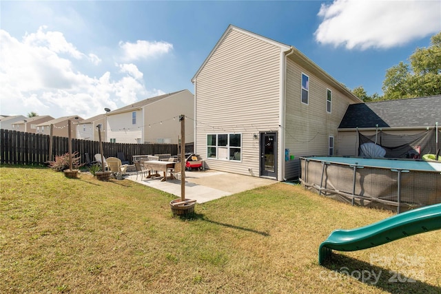 back of property featuring a lawn, a patio area, a playground, and a fenced in pool